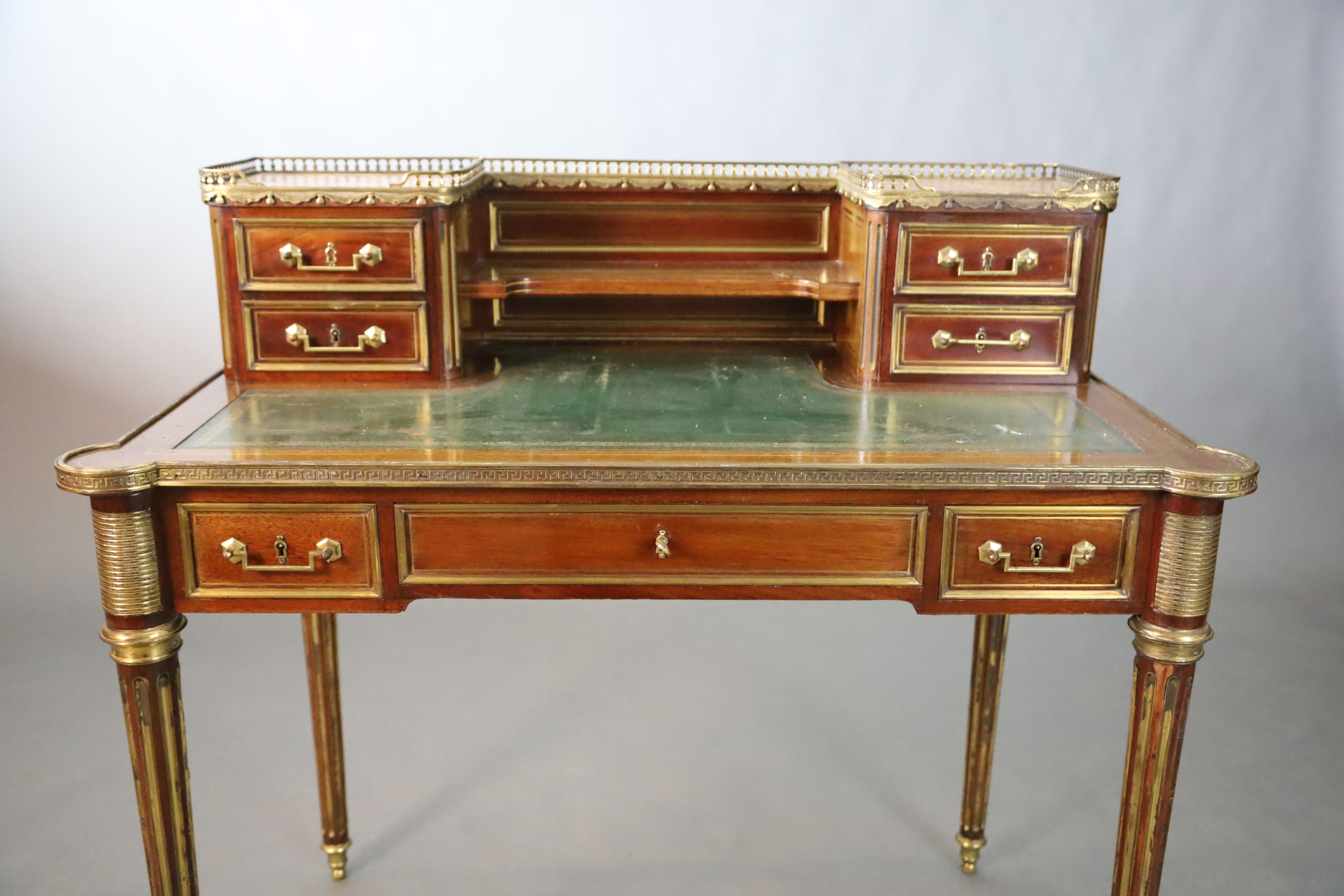 A French Louis XVI style brass mounted marble inset mahogany writing table, W.101.5cm D.7.5cm H.93.5cm